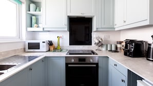 Une cuisine moderne avec des meubles de couleur bleu clair, un four Bosch, un four à micro-ondes et une machine à café.