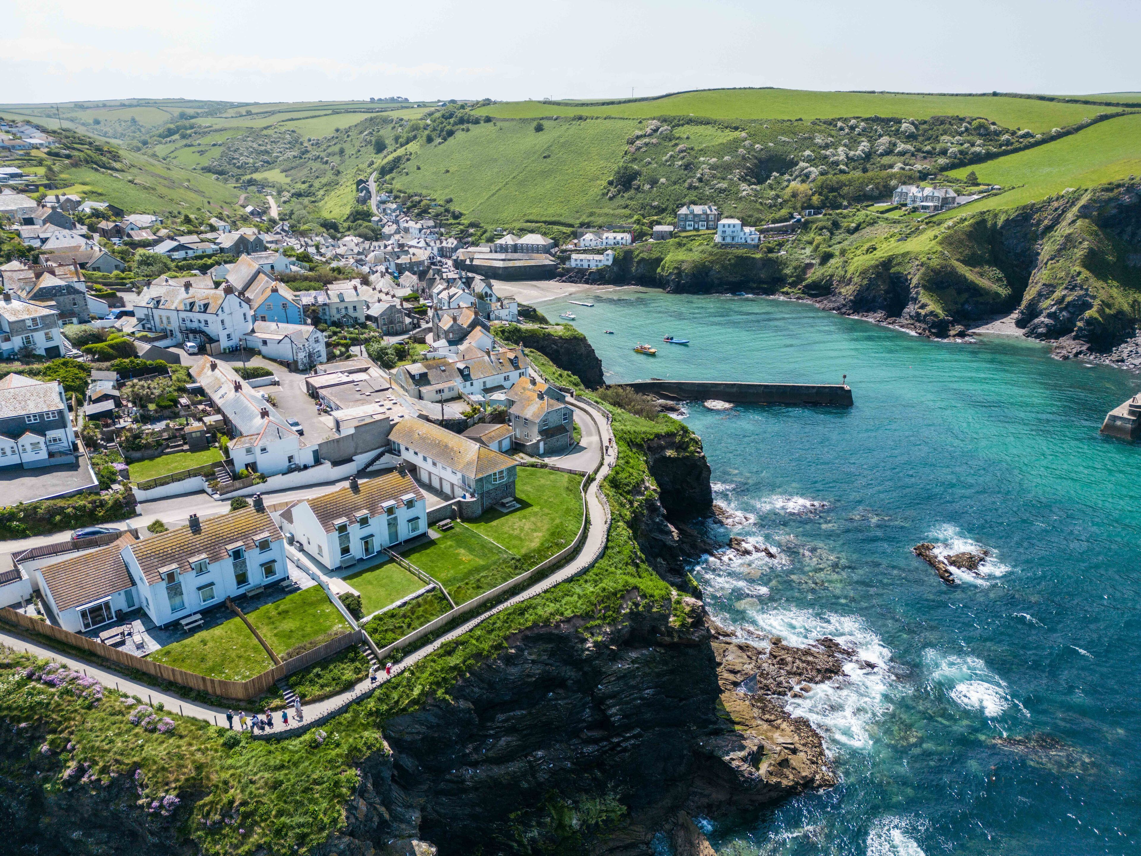 A coastal village with white buildings, a winding road, and a rocky coastline.