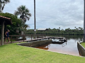 A calm water body with a wooden dock, a gazebo, and a person standing by the water.