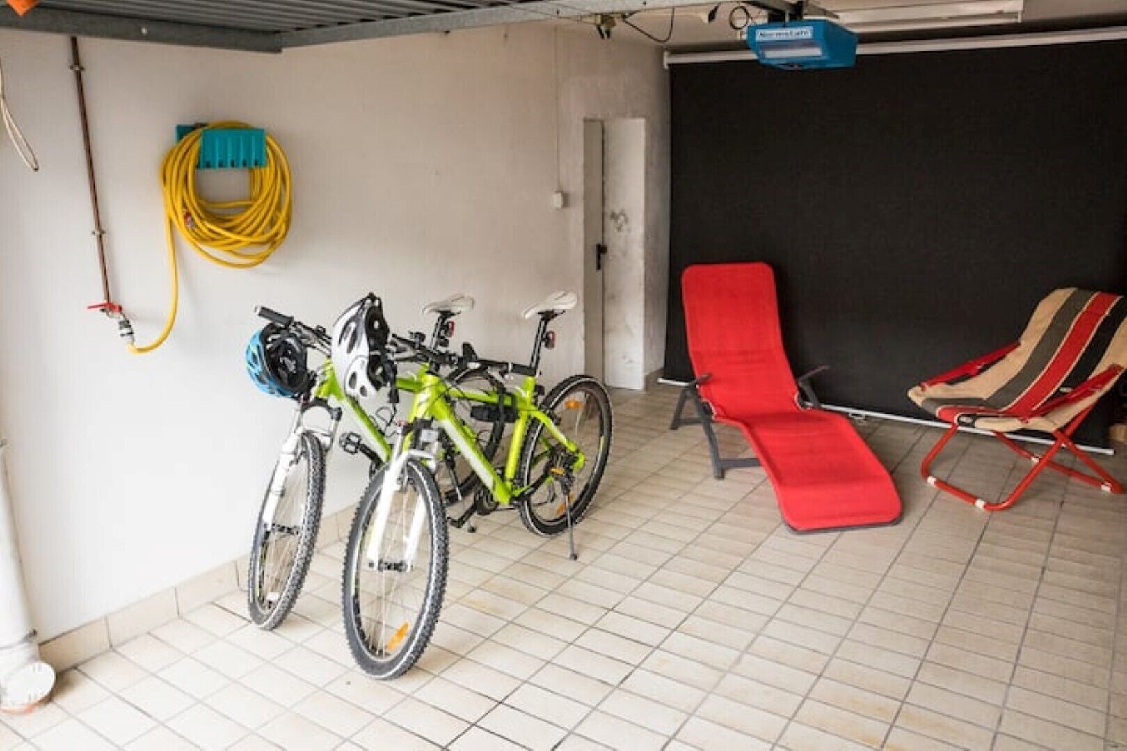 A garage with two bicycles, a red folding chair, and a yellow extension cord.