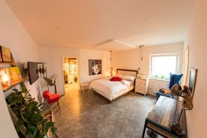 Quarto com cama, mesa de cabeceira e janela.