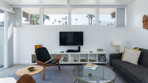 Un salon moderne avec un téléviseur à écran plat, un canapé, une table basse et un fauteuil.