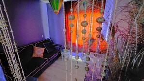 A room with a black sofa, a decorative hanging, and a patterned curtain.