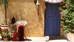 A traditional Moroccan courtyard with wicker furniture, potted plants, and a blue door.