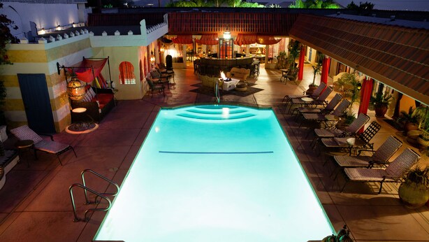 An outdoor swimming pool with lounge chairs and a bar area.