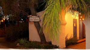 A sign welcoming to the spa garden, a pathway leading to a building, and a palm tree.