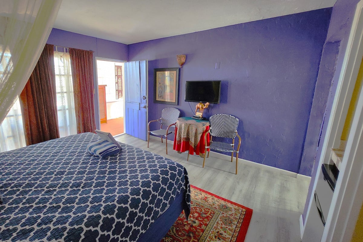 Ein Schlafzimmer mit Bett, Fernseher, Sessel und Tisch.