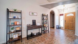 A hallway with three black metal shelves, a wooden console table, and a wooden door.