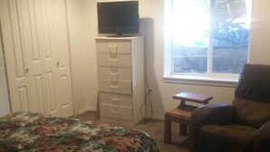 Une chambre à coucher avec un lit, une commode, un téléviseur posé sur le dessus, une chaise et une fenêtre donnant sur un beau paysage.