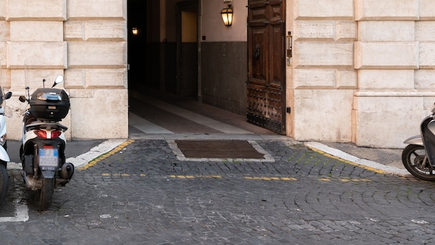 Un ingresso ad arco con balaustra in pietra, una porta in legno e una targa con il numero 3.