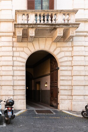 An arched entrance with a stone balustrade, a wooden door, and a number '3' sign.