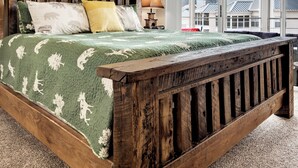 Ein Schlafzimmer mit einem hölzernen Bett, einem Deckenventilator, einem großen Fenster und einem gerahmten Bild an der Wand.