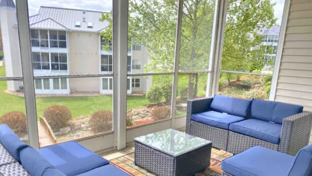 Ein überdachter Patio-Bereich mit Korbmöbeln und einem Glastisch.