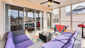 Eine überdachte Terrasse mit Schiebegläsern, Deckenventilator und Gartenmöbeln.