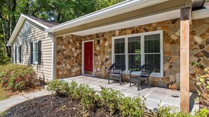 A house with a stone exterior, a red door, and a covered porch with two chairs. - WHOLE Home with BASEMENT on 3 Acres (Kennesaw)