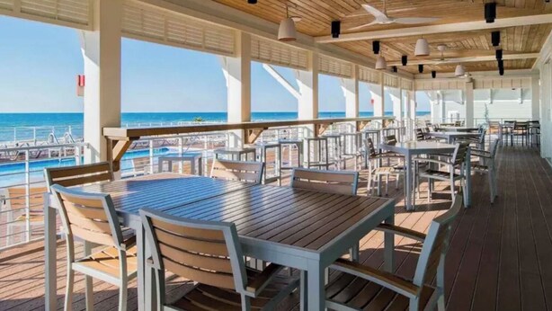 A covered outdoor dining area with tables and chairs, large windows, and a view of the ocean. - Beautiful & Beachy!
3BR Townhome Lost Key Golf & Beach Club, Pools, Free Shuttle (Pensacola)