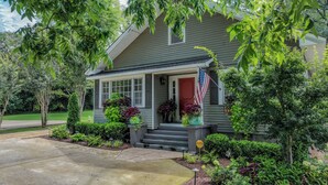 A two-story house with a front porch, a flag, and a well-maintained garden.