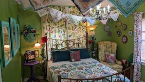 A room with a bed, a chair, a table, and a chandelier. - Escape to Wonderland (Oklahoma City)