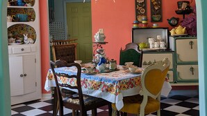 A dining area with a checkered floor, a table with a floral tablecloth, and chairs. - Escape to Wonderland (Oklahoma City)