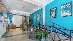 A lobby with teal walls, a staircase, and a reception desk. - Modern South Beach Studio (Miami Beach)
