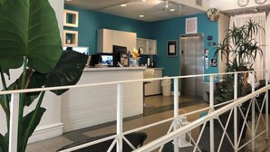 A modern hotel lobby with a reception desk, a kitchen area, and a staircase leading to upper floors. - Modern South Beach Studio (Miami Beach)