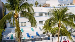 A hotel with a white facade, blue accents, and a pool area with lounge chairs. - Modern South Beach Studio (Miami Beach)