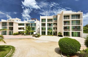A modern hotel with multiple floors, large windows, and a well-maintained garden area.