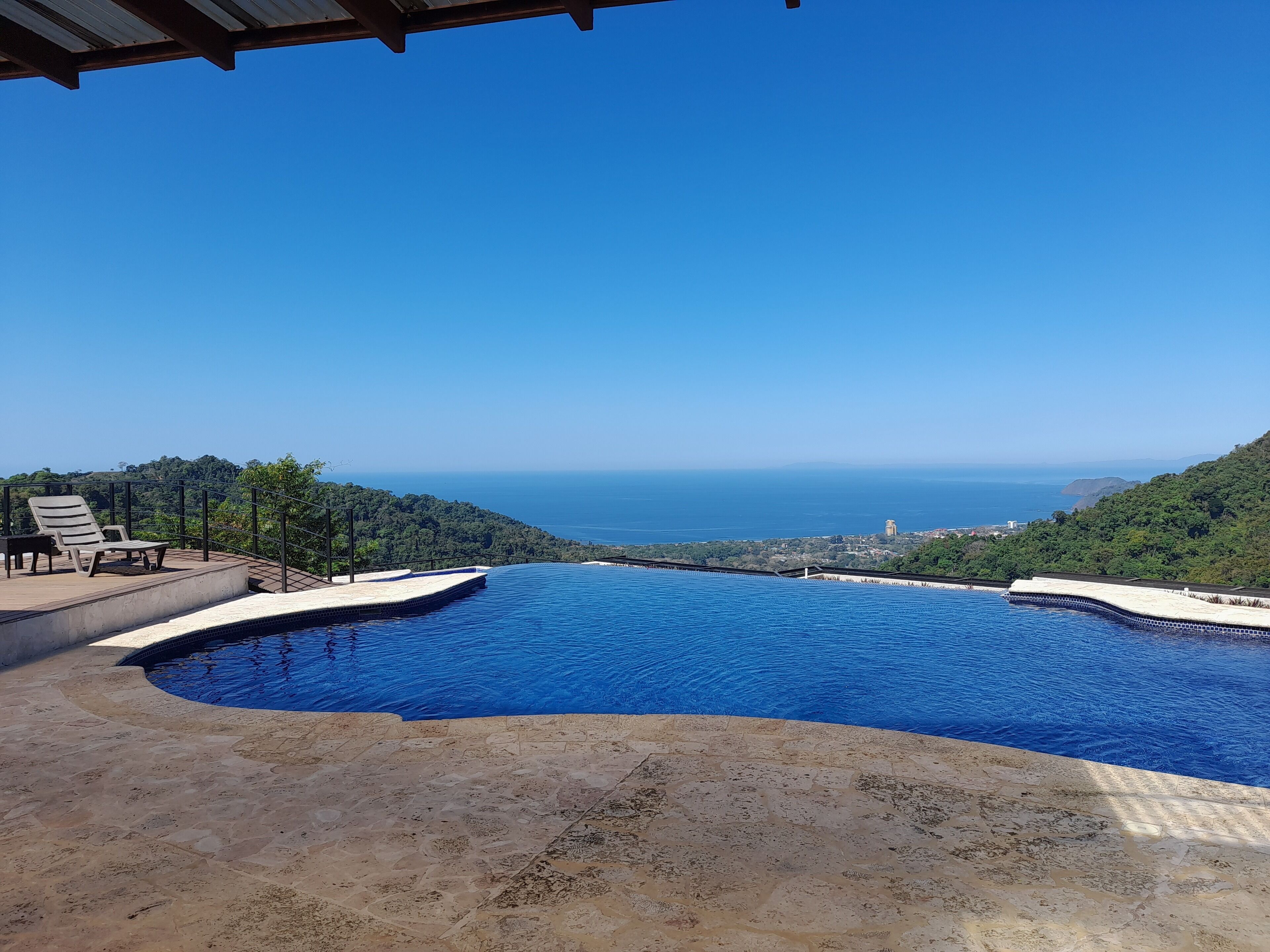 Una piscina infinita con vista al mar y las colinas.