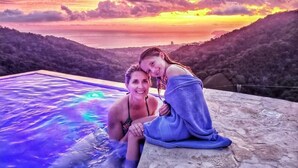 Una coppia seduta a bordo piscina con vista sul tramonto.