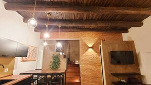A modern kitchen with a wooden ceiling, a dining area with chairs, and a TV mounted on the wall. - LOFT WITH INDEPENDENT ENTRANCE ON 2 FLOORS HISTORICAL CENTER (Napoli)