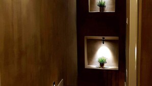 A hallway with wooden flooring and a sloped ceiling. There are two wall-mounted lights and a small potted plant on a shelf. - LOFT WITH INDEPENDENT ENTRANCE ON 2 FLOORS HISTORICAL CENTER (Napoli)