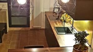 A modern kitchen with wooden flooring, a dining table with chairs, and pendant lights. - LOFT WITH INDEPENDENT ENTRANCE ON 2 FLOORS HISTORICAL CENTER (Napoli)