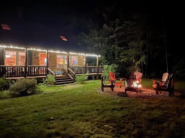 A log cabin with a deck, outdoor seating, and a fire pit. - Dog-Friendly 5 Bedroom Log Cabin with Hot Tub in the Heart of Southern Maine  (Brownfield)