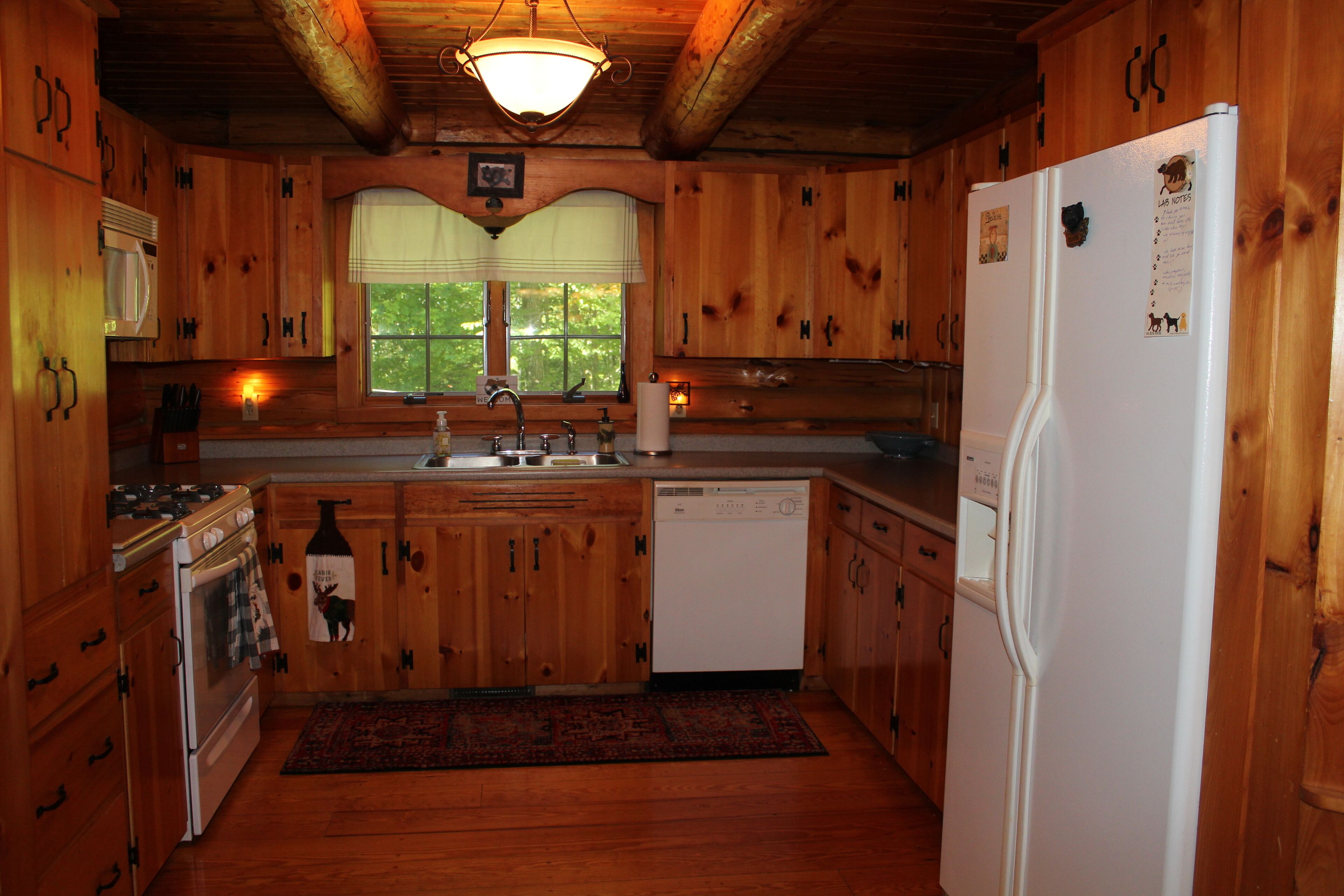 Eine Holzhütte mit einer Küche, inklusive Herd, Spüle, Kühlschrank und Holzschränken.