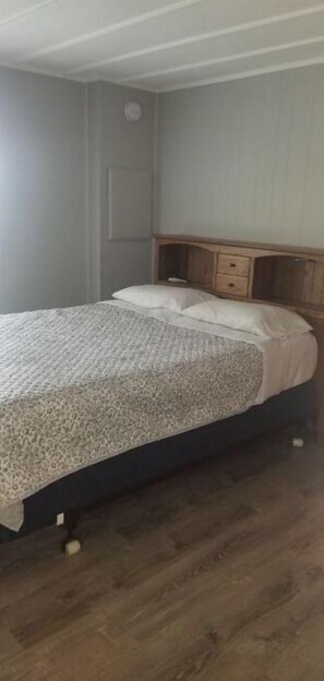 Un dormitorio con cama, cabecera de madera y mesita de noche.