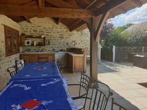 A rustic stone kitchen with wooden cabinets and a dining table set for two.