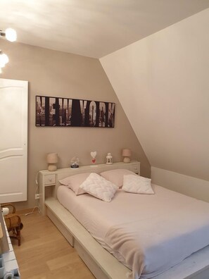 A bedroom with a bed, bedside tables, a wall-mounted artwork, and a sloped ceiling.
