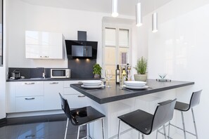 A modern kitchen with white cabinets, a black countertop island, and bar stools.