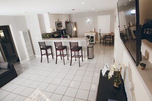Une cuisine moderne avec des meubles blancs, un îlot central doté de tabourets et un coin repas avec des chaises.