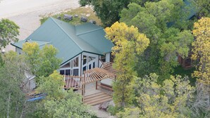 A house with a green roof, surrounded by trees and a wooden deck.