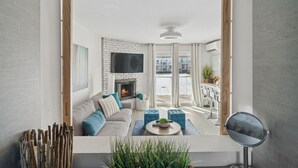 Un salon moderne avec une cheminée, un canapé, une table basse et une vue sur l’extérieur.