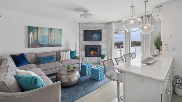 Un salon moderne avec un canapé, des poufs, une table basse et une cheminée.