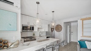 Une cuisine moderne avec des meubles blancs, des appareils en acier inoxydable et un îlot central doté de tabourets de bar.