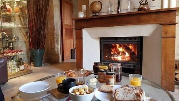 A breakfast setting with a fireplace, a glass table, and various breakfast items. - Cozy Cottage (Éméville)