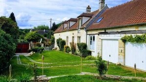 A residential property with a well-maintained lawn, a garage, and a sloped roof. - Cozy Cottage (Éméville)