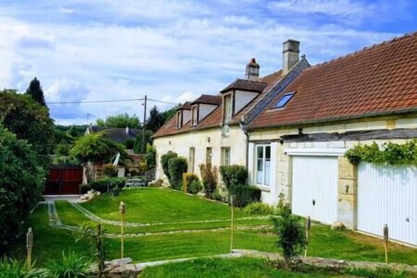 A residential property with a well-maintained lawn, a garage, and a sloped roof.