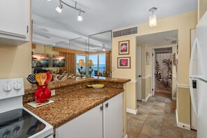 A kitchen with granite countertops, a white stove, and a red utensil holder.