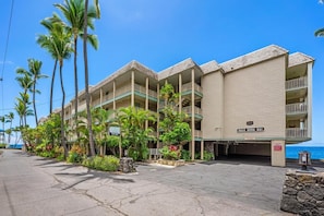 A hotel with multiple balconies, palm trees, and a view of the ocean.