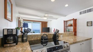 Una cocina equipada con estufa, horno, cafetera y televisión.
