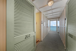 Un pasillo con puertas numeradas 212 y 213, que conduce a un balcón con vistas.